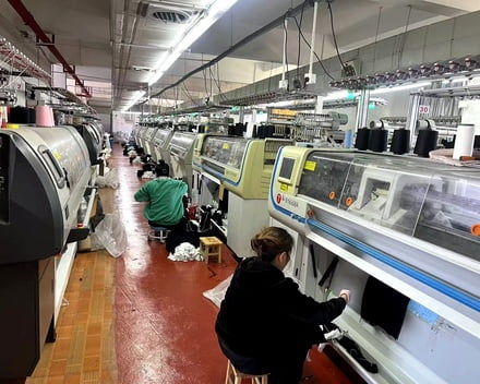 Workers performing finishing and sewing on knitted hats